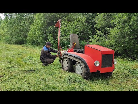 Mini tracked tractor mowing hay.
