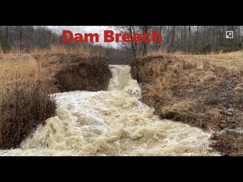 Large pond dam breach causes water surge down stream