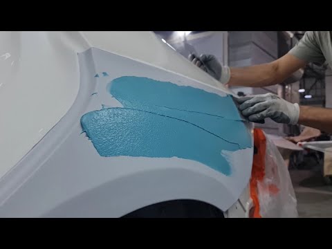 Маляр наносит эпоксидный грунт и конструктивную шпатлевку на алюминиевое крыло от Мерседеса