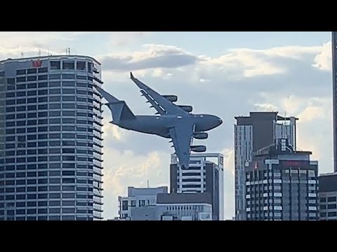 plane flies between buildings