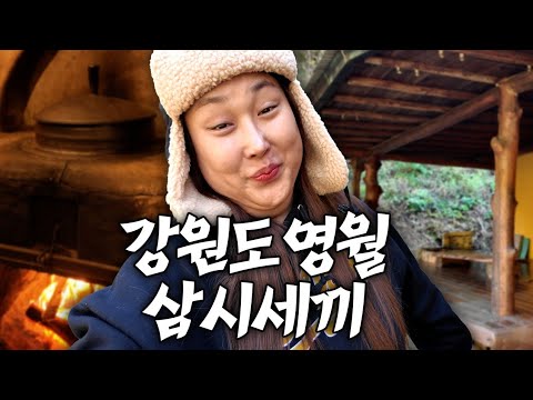 A bowl of kimchi stew with chives and samgyetang in a cauldron, buckwheat pancakes, a glass of ma...