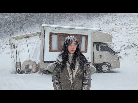 A truck camping in the snow, stranded in a continuous downpour.