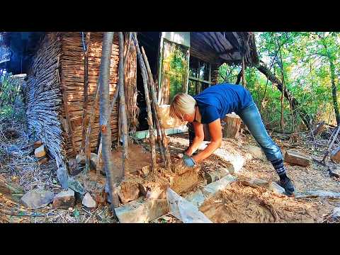 Woman builds a reed hut alone. A clay fireplace and wall insulation