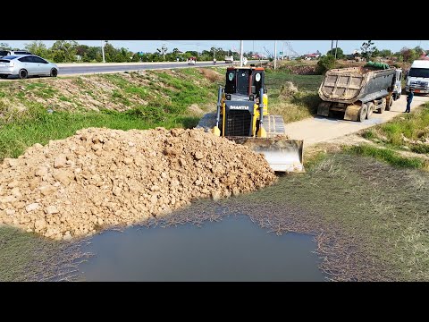 Nice bulldozer start new project pushing soil filling land with dump trucks