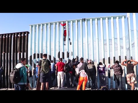 Immigrants climb over U.S. Mexico border wall