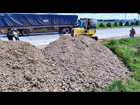 Great skill operator uses Komatsu D37 bulldozer pushing soil and filling land with dump trucks 
