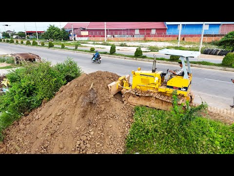 Great skill bulldozer Komatsu driver pushing soil with dump trucks filling land