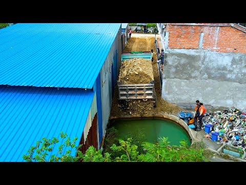 Bulldozer work hard in the narrow area push the stone and tree dump truck unload the stone