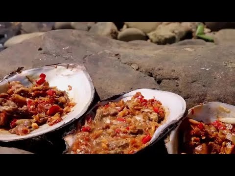 Old man barbecues river clams by the river, tears for delicious food