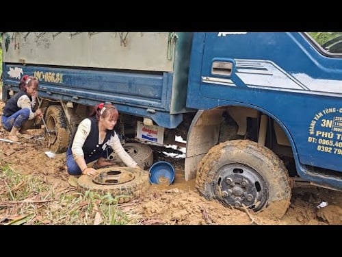 Girl repairs and restores a broken car wheel in the middle of the road.