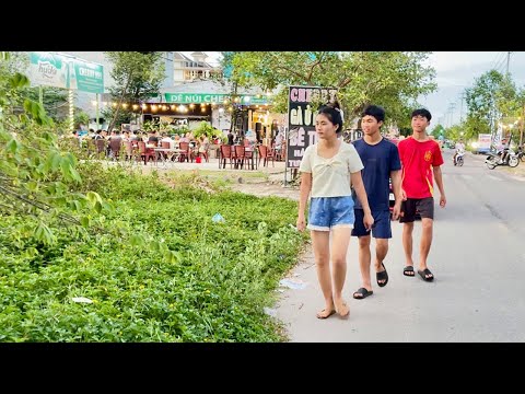 The sidewalk next to the restaurant is covered with grass and trash right on a busy small street.