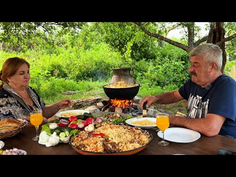 A real family dinner al fresco. Cooking pilaf in a cauldron over a campfire.