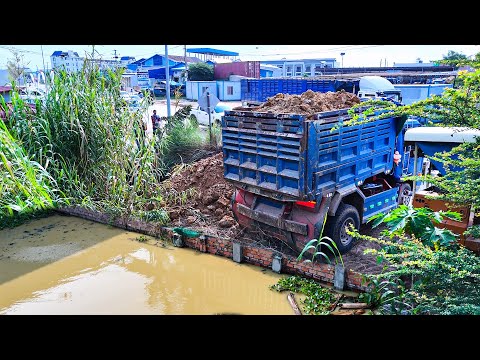 Nice skill bulldozer operator pushes soil filling up land with dump trucks unloading dirt